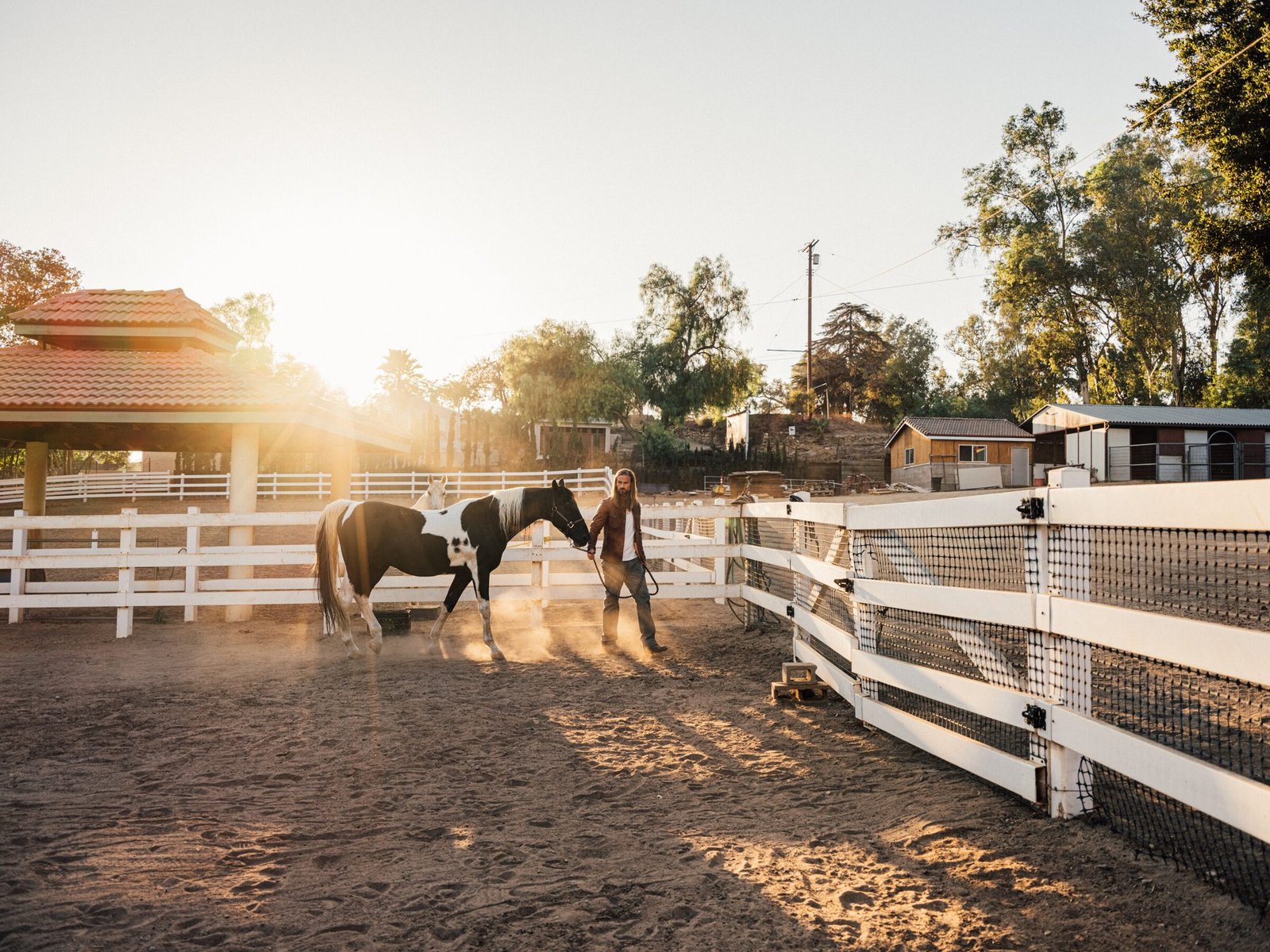 Horse and handler in a white-fenced riding arena at golden hour, Shadow Hills Ranch