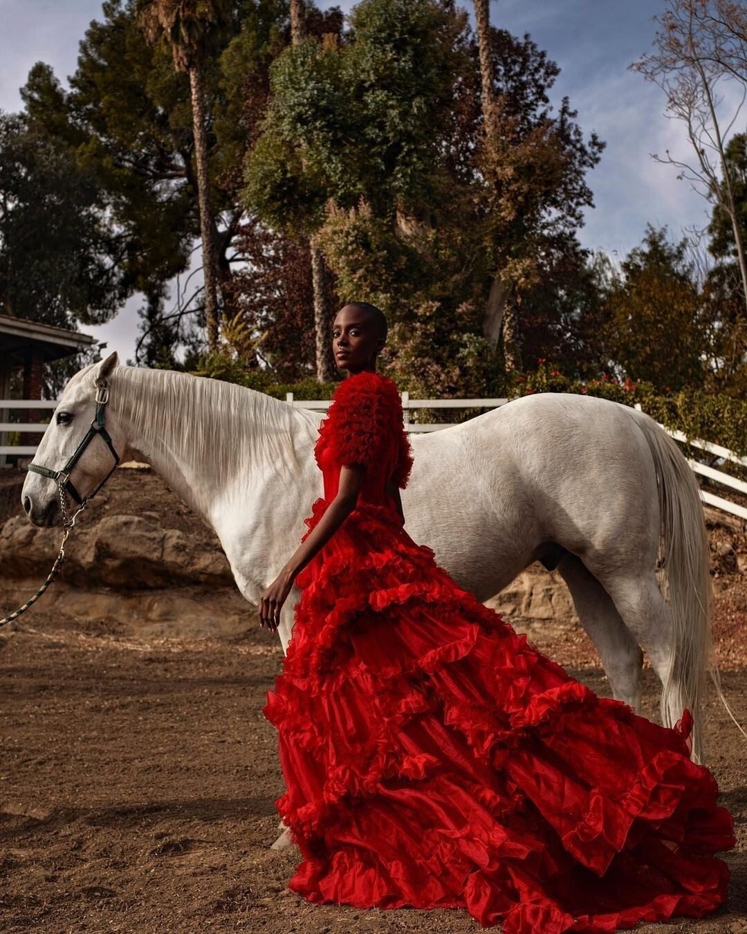 Fashion shoot with a model in a red gown beside a white horse at dusk, Shadow Hills Ranch