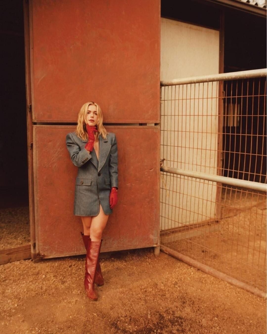 Model leaning on a red stall door, Shadow Hills Ranch